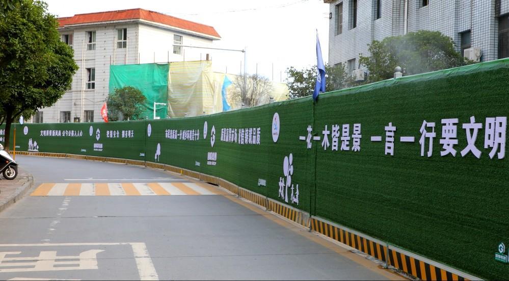 在城区20多个建筑工地设置绿皮围挡,张贴创文公益宣传标语,让工地围挡